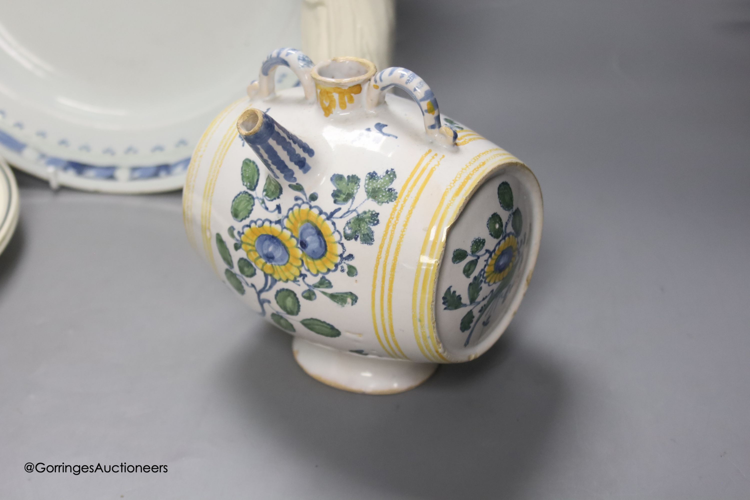 A Continental tin glaze dish, 18th/19th century, possibly Portuguese, a faience Gin barrel, a pottery figure, inscribed in pencil ‘I Barry’ and two Zell Creamware topographical plates